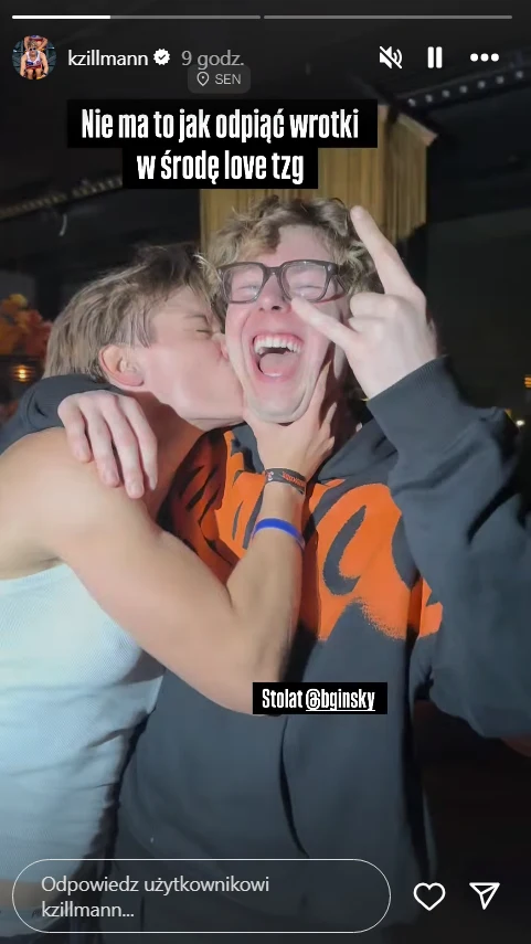 Katarzyna Zillmann i Mikołaj "Bagi" Bagiński Dwie młode osoby w radosnej atmosferze, jedna całuje drugą w policzek, druga uśmiecha się szeroko i robi znak pokoju palcami, obie wyglądają na zadowolone i wesołe.