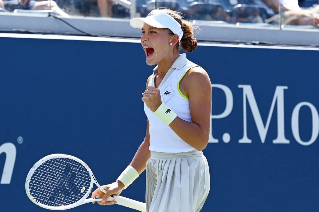 Erika Andriejewa to starsza siostra Mirry Tenisistka w sportowym stroju wykrzykuje z uniesioną pięścią, trzymając rakietę tenisową na korcie podczas zawodów sportowych.