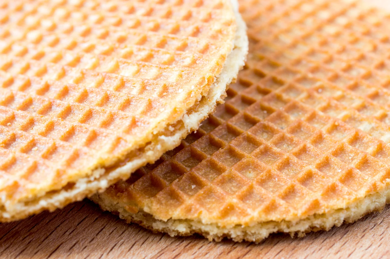 Sieć Lidl wycofała partię wafli z nadzieniem karmelowym Dwa cienkie, okrągłe wafle z widoczną fakturą kratki, leżące na drewnianej powierzchni.