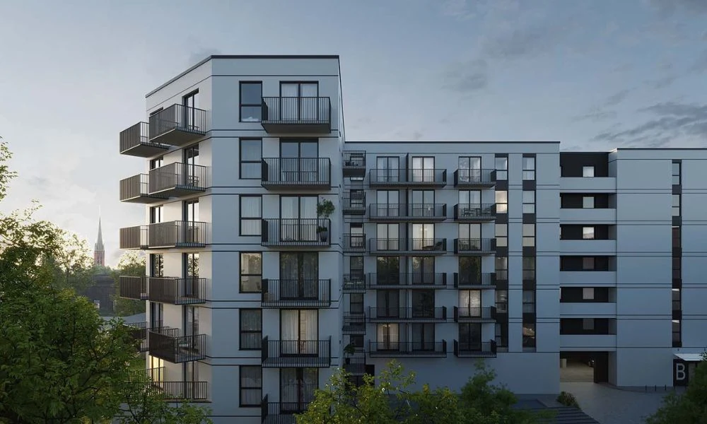 Mieszkaniowy Dzień Otwarty Nowoczesny budynek mieszkalny z dużymi oknami oraz balkonami, otoczony zielenią, o jasnej elewacji i regularnych kształtach, z wyraźnie widoczną bryłą oraz kilkoma kondygnacjami.