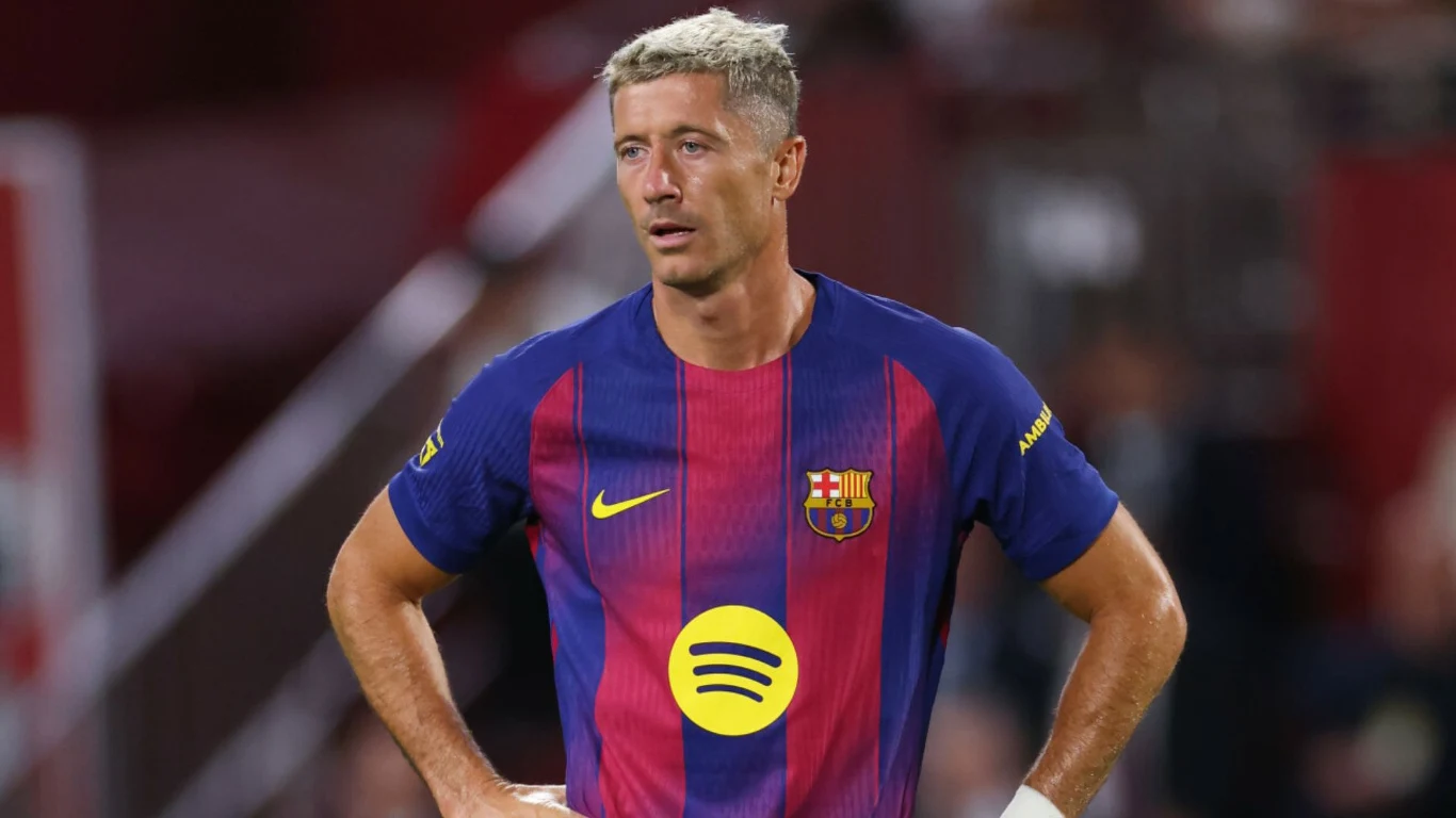 Piłkarz w stroju FC Barcelony z charakterystycznym herbem klubu i logotypem sponsora na koszulce, podczas meczu na stadionie, z poważnym wyrazem twarzy, ręce wspiera na biodrach.