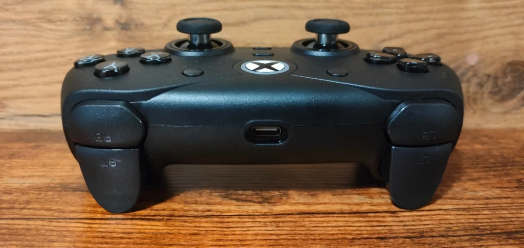 Hyperkin Competitor Czarny kontroler do konsoli Xbox ustawiony na drewnianej powierzchni, widoczne złącze USB typu C oraz przyciski z przodu urządzenia.