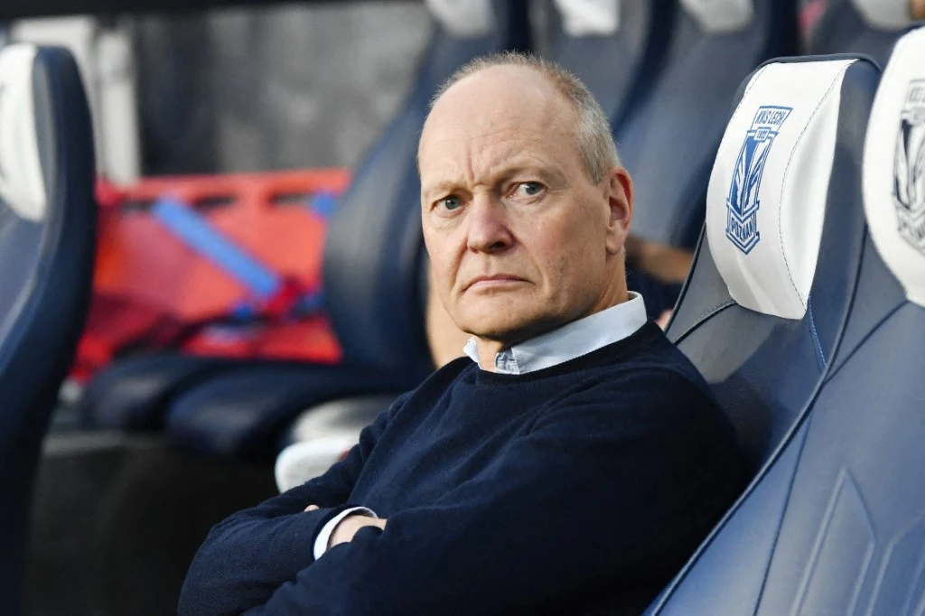 Lech Poznań przegrał z mistrzem Gibraltaru Mężczyzna w średnim wieku z poważnym wyrazem twarzy siedzi na stadionowym krześle z logotypem sportowym, ujęcie skupione na jego sylwetce i mimice.