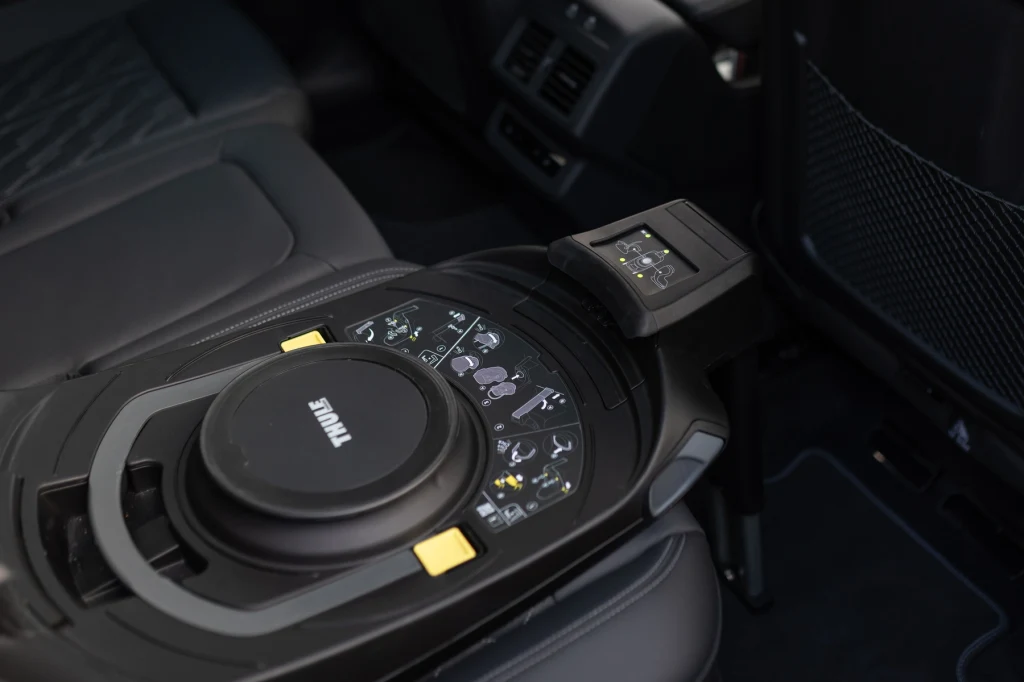 Konsola środkowa w luksusowym aucie wyposażona w panel sterowania oraz pokrętła z wyświetlaczem dotykowym i miejscem na napój. Fotele wykonane z wysokiej jakości materiału, przestrzeń czysta i nowoczesna.
