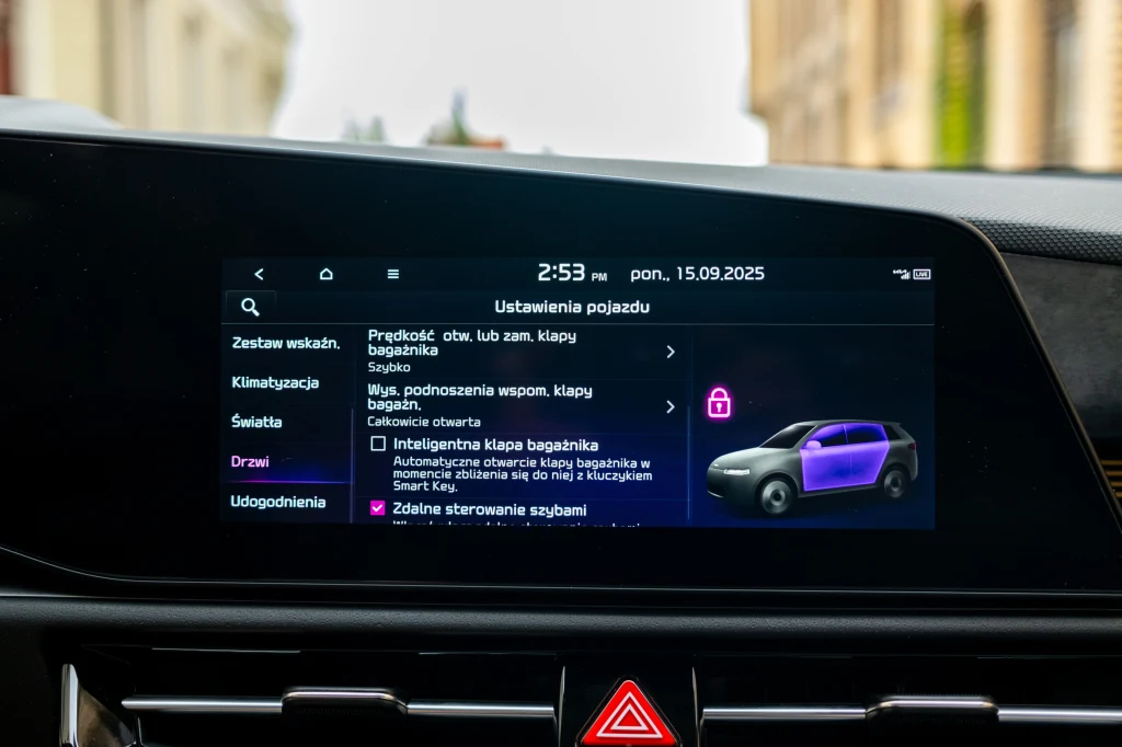 Wyświetlacz samochodowy prezentujący ustawienia pojazdu, skupiający się na konfiguracji drzwi i bagażnika, z graficzną wizualizacją samochodu oraz ikoną informującą o zamknięciu drzwi.
