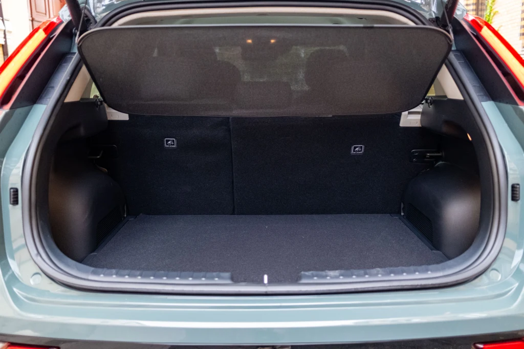 Otwarty, pusty bagażnik samochodu z widocznymi osłonami bocznymi oraz rozłożoną osłoną przestrzeni bagażowej. Tapicerka w ciemnym kolorze, wykończenie schludne i nowoczesne.