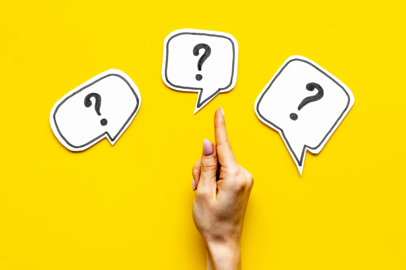 Kultowi bohaterowie, uwielbiane serie, niesamowite światy. Ten quiz to powrót do ulubionych produkcji! Uniesiona dłoń wskazująca na jeden z trzech papierowych dymków z narysowanymi znakami zapytania na żółtym tle.