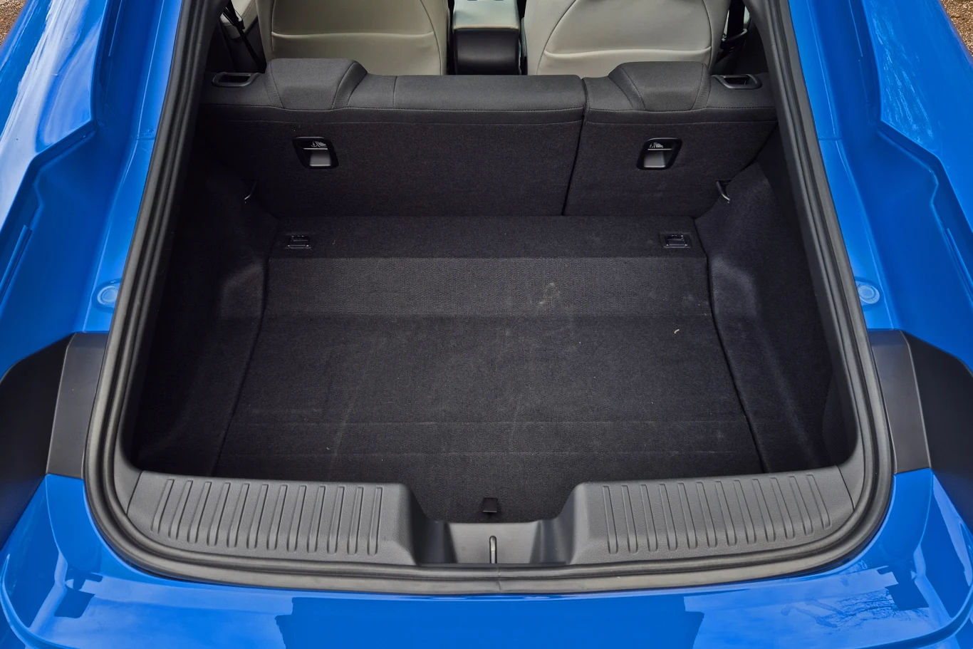 Bagażnik Prelude ma niewielką pojemność 264 l i nieco nieregularny kształt Pojemny bagażnik samochodu o wyściełanej powierzchni i wysokich bocznych ściankach, otoczony niebieską karoserią, z widocznymi częściami tylnych siedzeń.