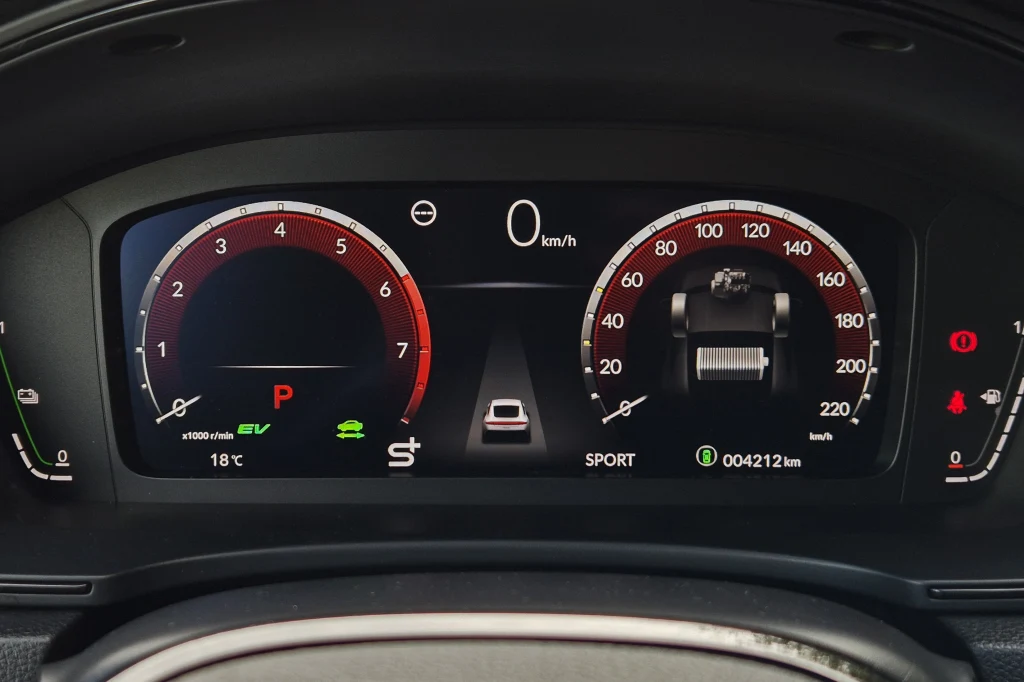 Wyświetlacz wskaźników ma 10,2 cala i nie daje zbyt wielu możliwości konfiguracji Wnętrze samochodu ze szczegółowym widokiem cyfrowego panelu wskaźników zawierającego prędkościomierz, obrotomierz, kontrolki, wskaźniki zużycia paliwa i temperatury oraz informacje dotyczące trybu jazdy i przebiegu.