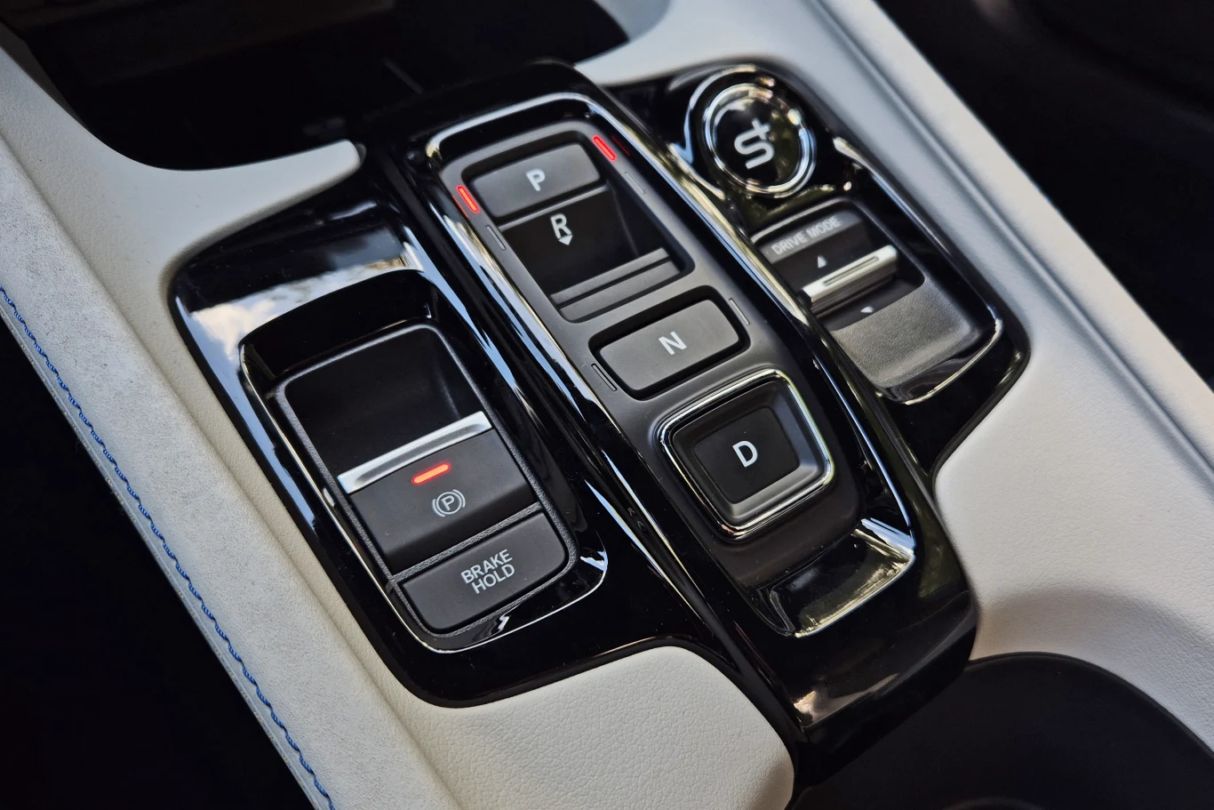 Przełączniki kierunku jazdy znamy dobrze z innych modeli Hondy. Tym co występuje tylko w Prelude jest przycisk S+, aktywujący symulowanie 8-biegowej przekładni Panel centralny samochodu z elektroniczną dźwignią zmiany biegów, przyciskiem hamulca postojowego i przyciskiem trybu sportowego. Połączenie czerni, srebrnych i białych elementów wnętrza.