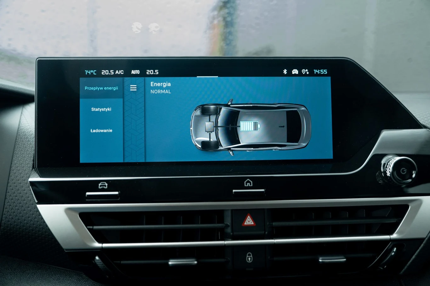 Wyświetlacz centralny samochodu pokazujący stan energii elektrycznej pojazdu oraz szczegóły dotyczące ładowania i statystyk energetycznych. Na ekranie widoczny schemat samochodu oraz interfejs użytkownika.