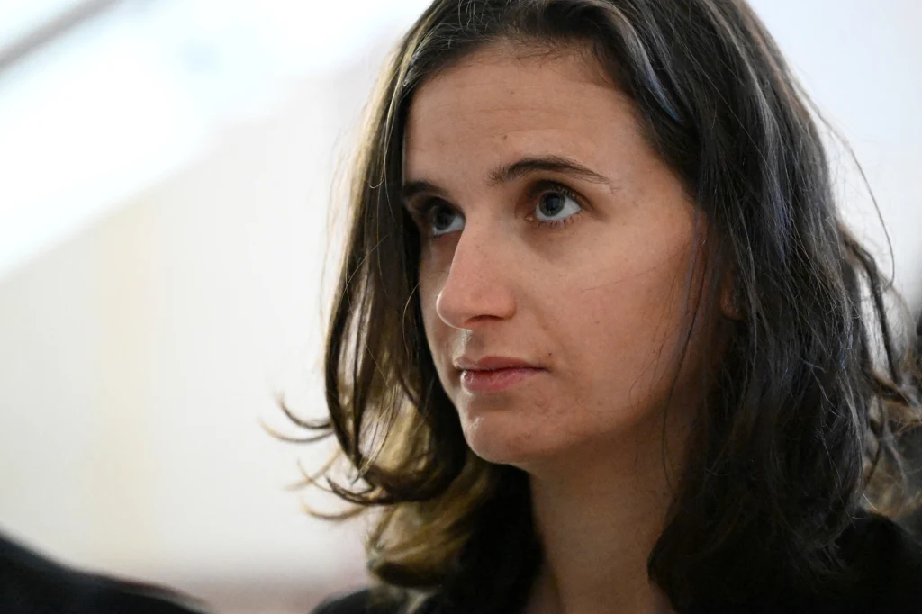 Kobieta o długich, ciemnych włosach i jasnej cerze, patrząca nieco w górę z poważnym wyrazem twarzy, sfotografowana w lekkim półprofilu.