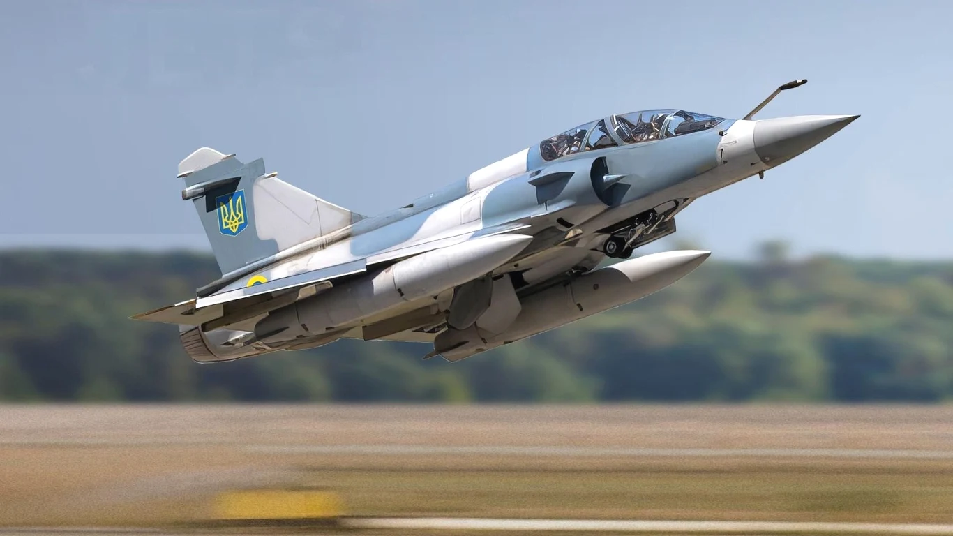 Francja wysyła Ukrainie potężne myśliwce Mirage 2000-5F Wojskowy odrzutowiec startuje z pasa startowego, w tle rozmyte drzewa i niebo, maszyna oznaczona żółto-niebieskim godłem na stateczniku.