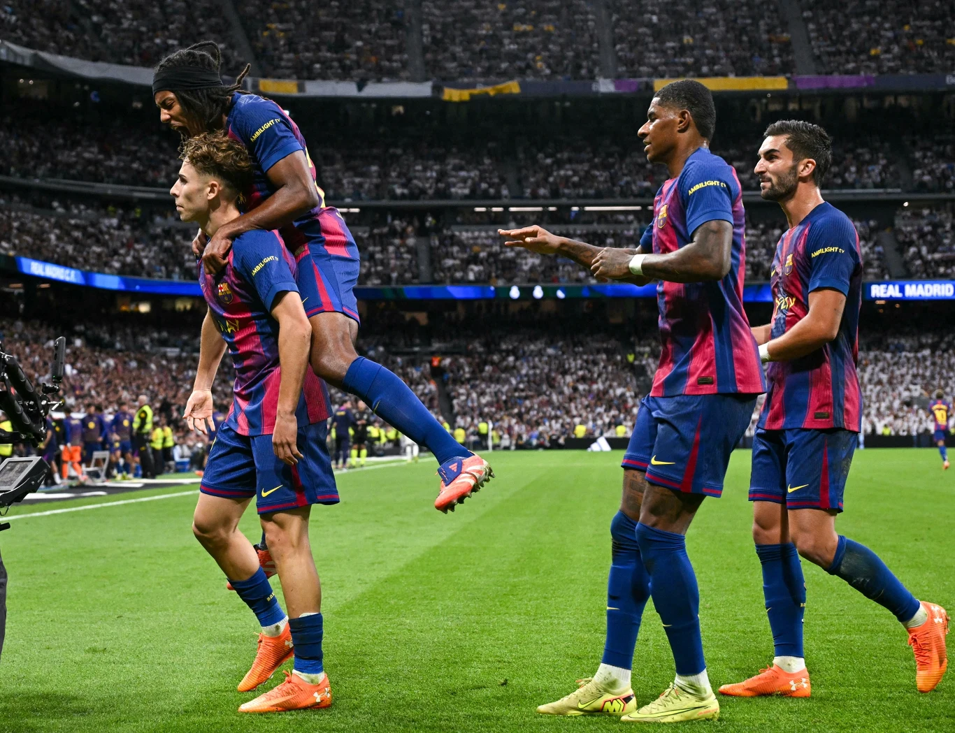 Jeszcze przed przerwą Barcelona miała moment satysfakcji po wyrównującej bramce Fermina Lopeza Piłkarze drużyny w niebiesko-czerwonych strojach świętują zdobycie bramki podczas meczu na stadionie pełnym kibiców, jeden z zawodników podskakuje na plecy kolegi.