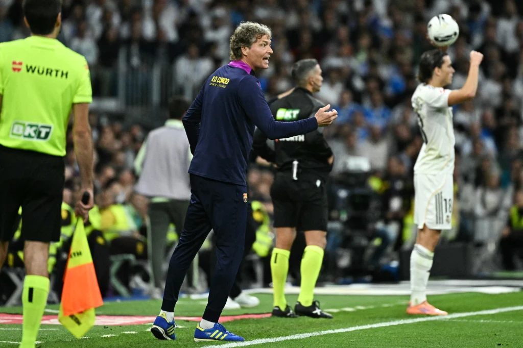 Marcus Sorg w roli dyrygenta przy linii bocznej Trener w sportowym stroju wydaje polecenia swoim zawodnikom podczas meczu piłki nożnej, w tle sędziowie liniowi w żółtych koszulkach oraz piłkarz drużyny przeciwnej wykonujący wrzut z autu.