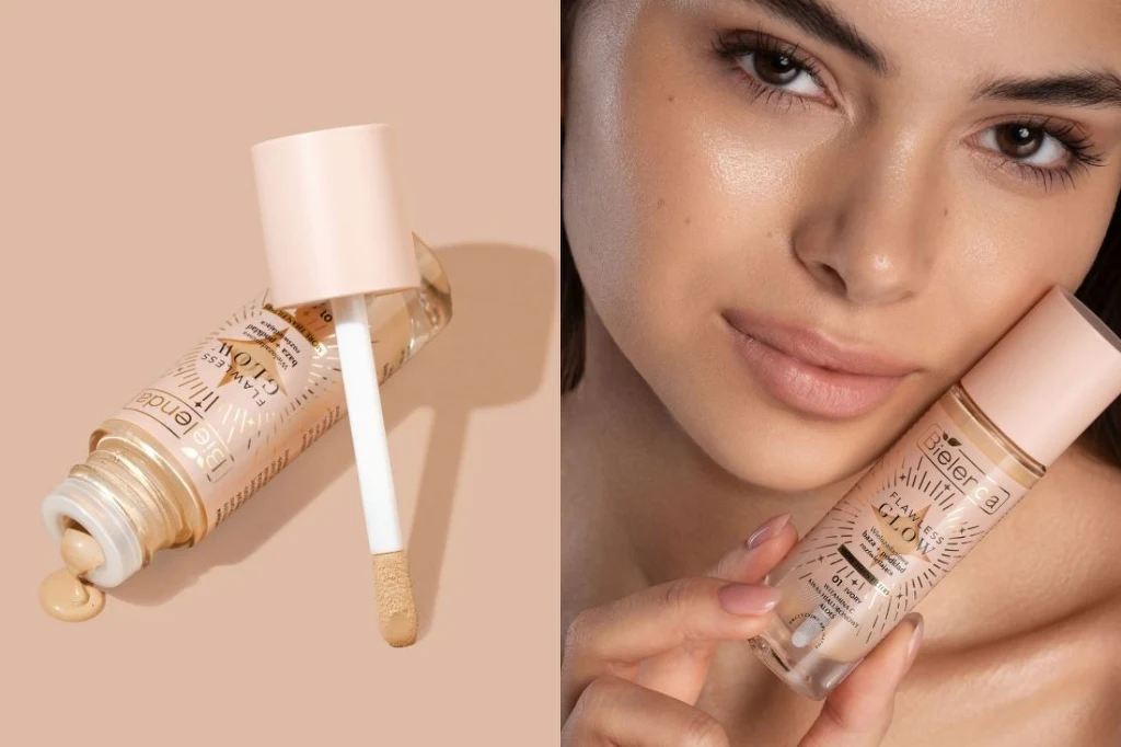 Kobieta o jasnej karnacji z naturalnym makijażem trzyma w dłoni buteleczkę podkładu z jasnozłotą zakrętką i aplikatorem, obok na beżowym tle leży otwarta butelka tego samego kosmetyku, z widoczną kroplą produktu przy ujściu.