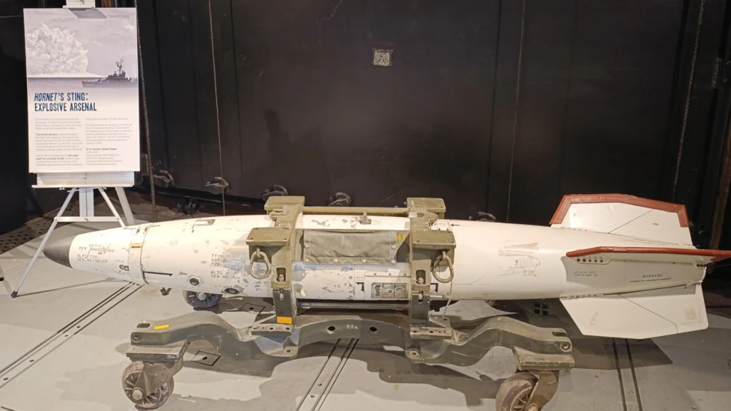 Model bomby atomowej B57 na USS Hornet Rakieta powietrze–ziemia ustawiona na specjalnym wózku transportowym w muzealnym wnętrzu obok planszy informacyjnej opisującej jej historię i specyfikację.