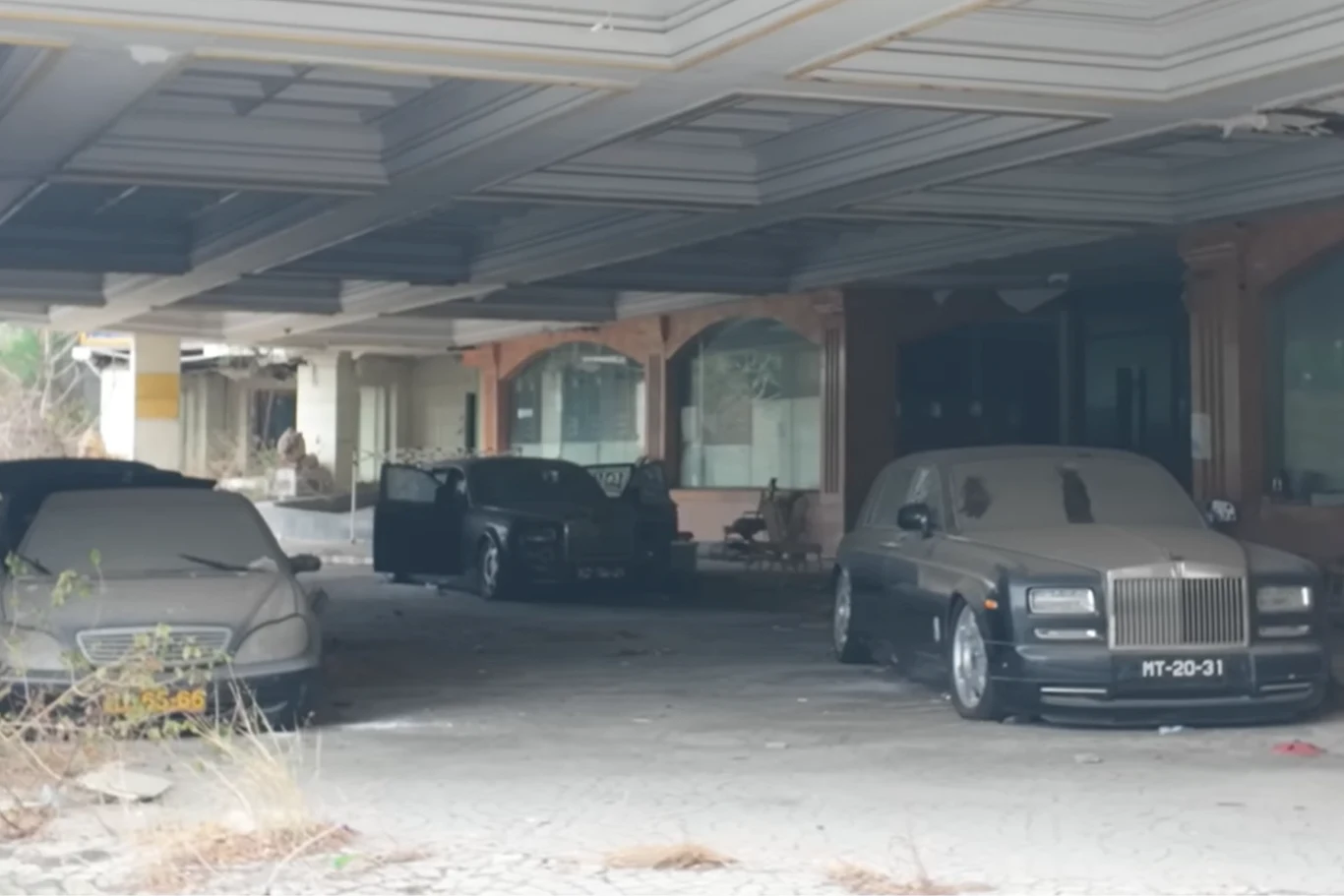 Lokalizacja krąży po internecie i pojawiły się już pierwsze kradzieże części. - Fot. YouTube - Exploring the Unbeaten Path Kilka luksusowych samochodów, w tym Rolls-Royce i Mercedes, stoi zakurzonych i opuszczonych pod zadaszeniem w zaniedbanym, opuszczonym budynku z pustymi witrynami.