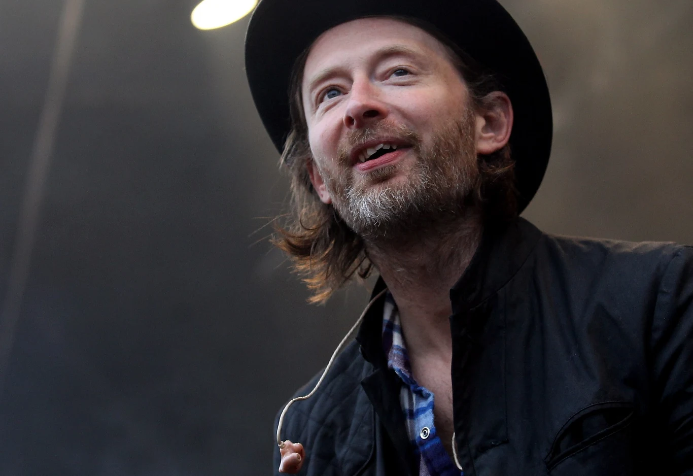 Utwór "Let Down" Radiohead odzyskał popularność dzięki TikTokowi Mężczyzna z zarostem w czarnym kapeluszu i ciemnej kurtce, uśmiecha się, patrząc lekko w bok, na tle ciemnego, rozmytego tła z jasnym światłem w górnej części kadru.