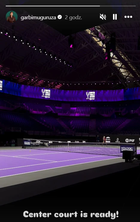 Garbine Muguruza pokazała, że kort centralny w Rijadzie jest gotowy. A w oddali... Iga Świątek Oświetlony kort tenisowy w dużej hali, fioletowe światła podkreślają centralną arenę, trybuny są puste, na ekranach widoczne logotypy turnieju oraz sponsorów, atmosfera przygotowań przed rozpoczęciem meczu.