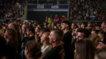 Tłum ludzi wpatrzony w scenę podczas koncertu lub wydarzenia muzycznego, z wyraźnie oznaczoną salą Atlas Arena w tle.