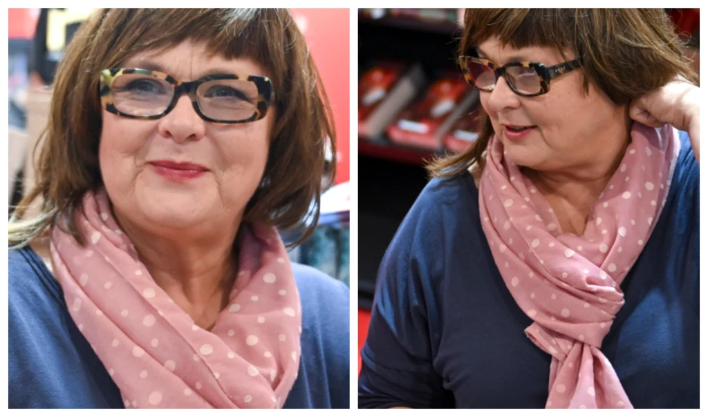 Edyta Jungowska na Międzynarodowych Targach Książki w Krakowie Kobieta w okularach z ciemnymi oprawkami, ubrana w różowy szal w białe kropki oraz granatową bluzkę. Delikatny makijaż, brązowe włosy do ramion, otoczenie sugeruje miejsce publiczne lub sklep.