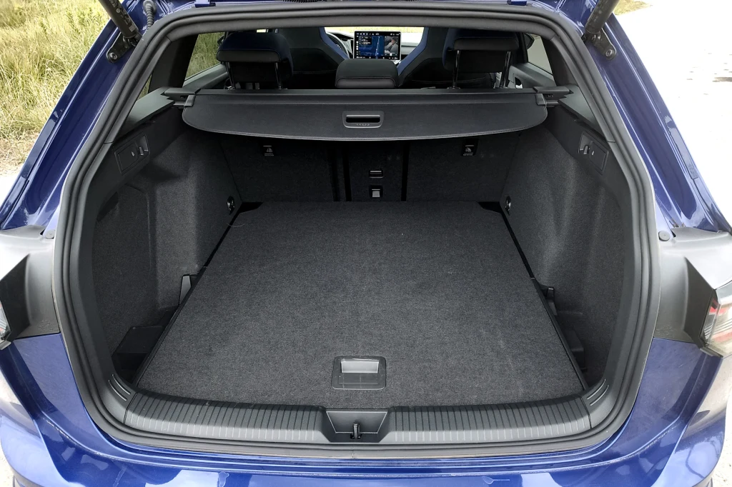 Bagażnik Volkswagena Golfa imponuje rozmiarami Otwarty bagażnik samochodu z dużą, pustą powierzchnią ładunkową oraz wysuniętą roletą oddzielającą przestrzeń bagażową od wnętrza pojazdu.