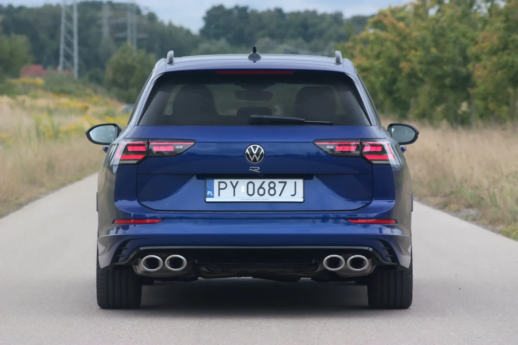 Volkswagen Golf R Niebieski samochód marki Volkswagen, widok od tyłu na drodze otoczonej zielenią. Widoczna polska tablica rejestracyjna i podwójny wydech po obu stronach tylnego zderzaka.