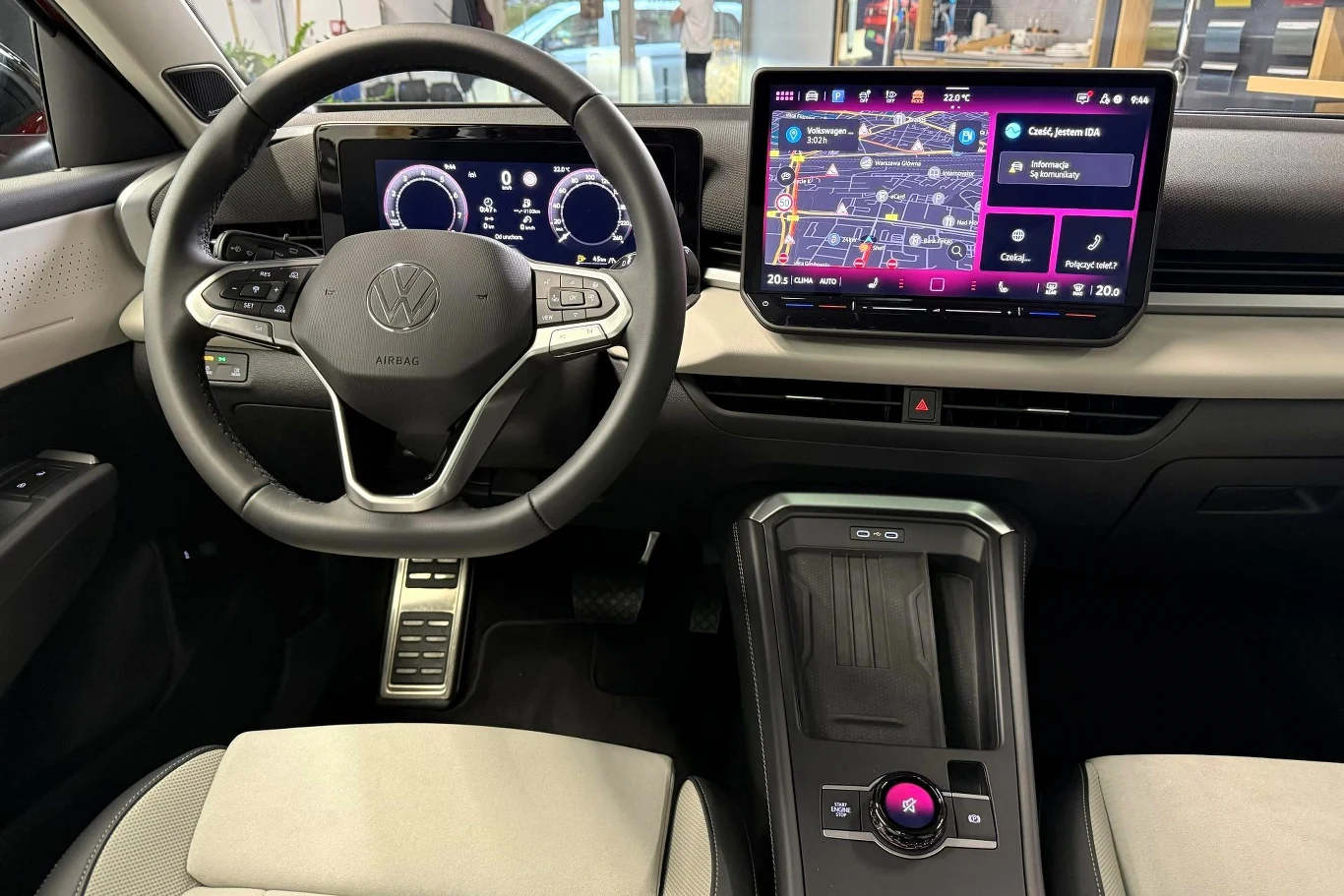 Nowoczesna deska rozdzielcza Volkswagena z cyfrowymi wyświetlaczami, dużym ekranem dotykowym z nawigacją, wielofunkcyjną kierownicą oraz elegancką konsolą środkową z minimalistycznymi przyciskami.