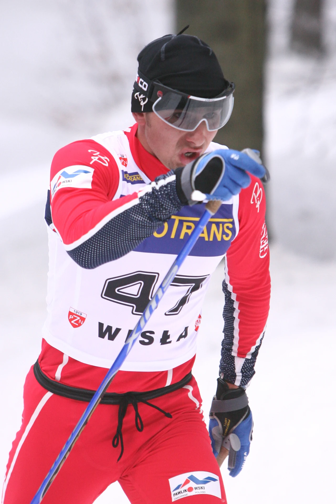 Kamil Fundanicz w 2007 roku Narciarz biegowy w czerwono-białym kombinezonie sportowym, z numerem startowym 47, biegnie przez zaśnieżony las, trzymając kije i nosząc sportowe okulary oraz czarną czapkę.