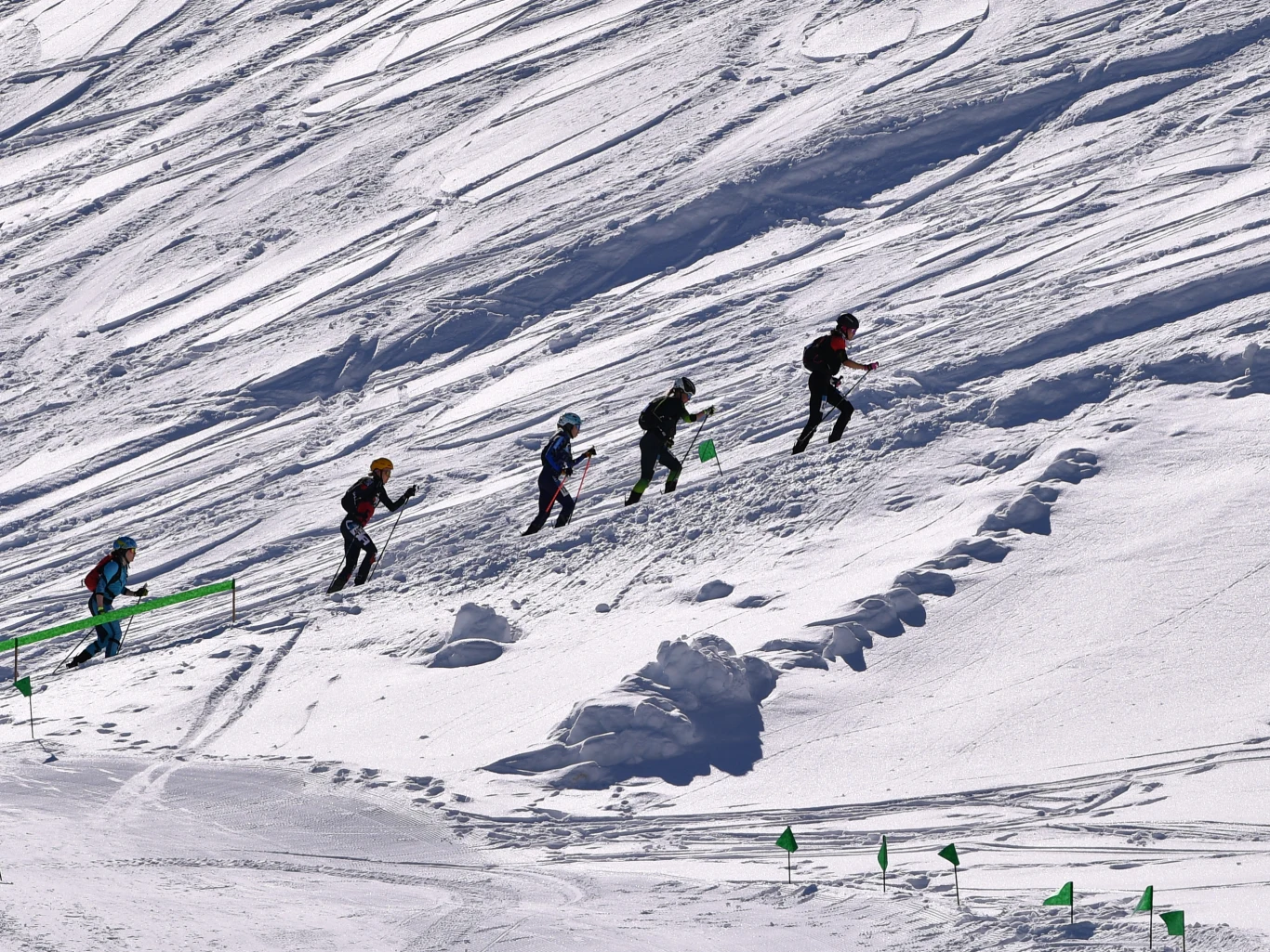 Skialpinizm to dyscyplina, która debiutuje na zimowych igrzyskach olimpijskich Czterech narciarzy wspina się pod górę po zaśnieżonym stoku, obierając trasę wyznaczoną przez zielone chorągiewki, ubrani w kaski i sportową odzież.