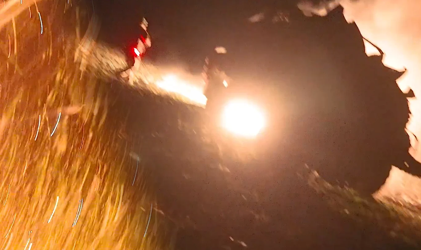 Dziennikarze "Die Welt" relacjonowali pracę Ukraińców, gdy uderzył rosyjski dron Pojazd wojskowy w ruchu podczas nocnej operacji, intensywne światło reflektorów, smugi ognia i dymu, sylwetka człowieka z tyłu, dynamiczna i chaotyczna atmosfera.