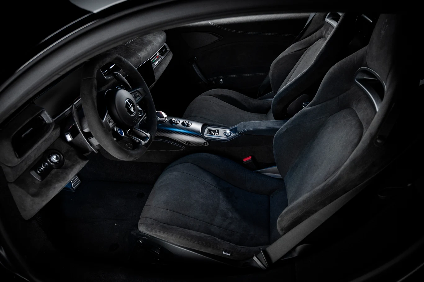 Czarna tapicerka foteli kubełkowych, sportowa kierownica, nowoczesna deska rozdzielcza oraz konsola środkowa z przyciskami sterującymi.
