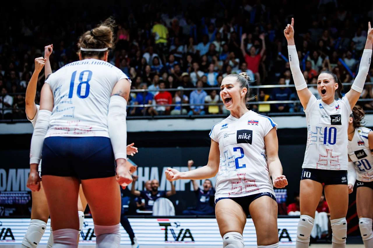 Zawodniczki drużyny siatkarskiej w białych strojach świętują zdobycie punktu podczas meczu, na twarzach widoczne są emocje i radość, a kibice obserwują wydarzenia na tle trybun.