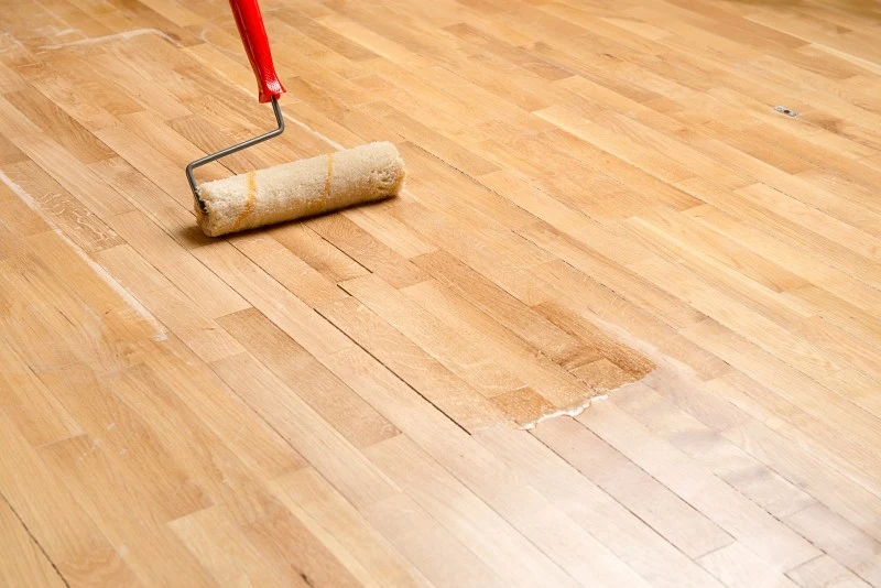 Po wypełnieniu szczelin drewnianą podłogę można lakierować lub malować