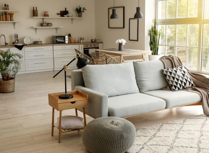 Jasna kuchnia, drewniane dodatki i beżowe ściany to idealne tło dla otwartej przestrzeni mieszkania