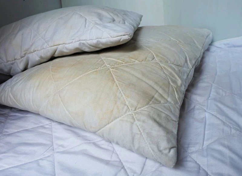 Żółte i brązowe plamy na poduszce pojawiają się na skutek pocenia się i ślinienia w trakcie snu