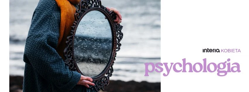 Zrozum swoje emocje i odkryj, jak wpływają na codzienne wybory Postać ubrana w niebieski płaszcz trzyma okrągłe, ozdobne lustro, w którym odbija się pochmurne niebo i szare morze. Po prawej stronie widoczne napisy 'interia kobieta' oraz 'psychologia'.