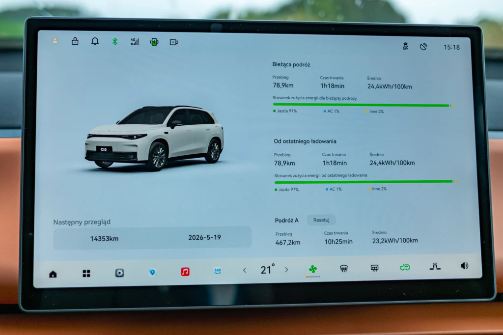 Wyświetlacz pokazuje komputer pokładowy samochodu elektrycznego, na którym widać statystyki dotyczące przebytej trasy, zużycia energii, przewidywanego terminu przeglądu oraz wizualizację auta.