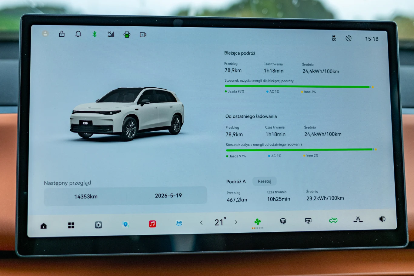 Wyświetlacz pokazuje komputer pokładowy samochodu elektrycznego, na którym widać statystyki dotyczące przebytej trasy, zużycia energii, przewidywanego terminu przeglądu oraz wizualizację auta.