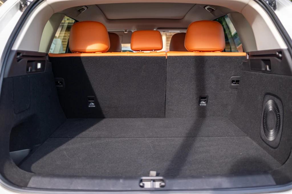 Pojemny bagażnik samochodu z widocznymi pomarańczowymi zagłówkami tylnej kanapy i czarną tapicerką, bez żadnych przewożonych przedmiotów.