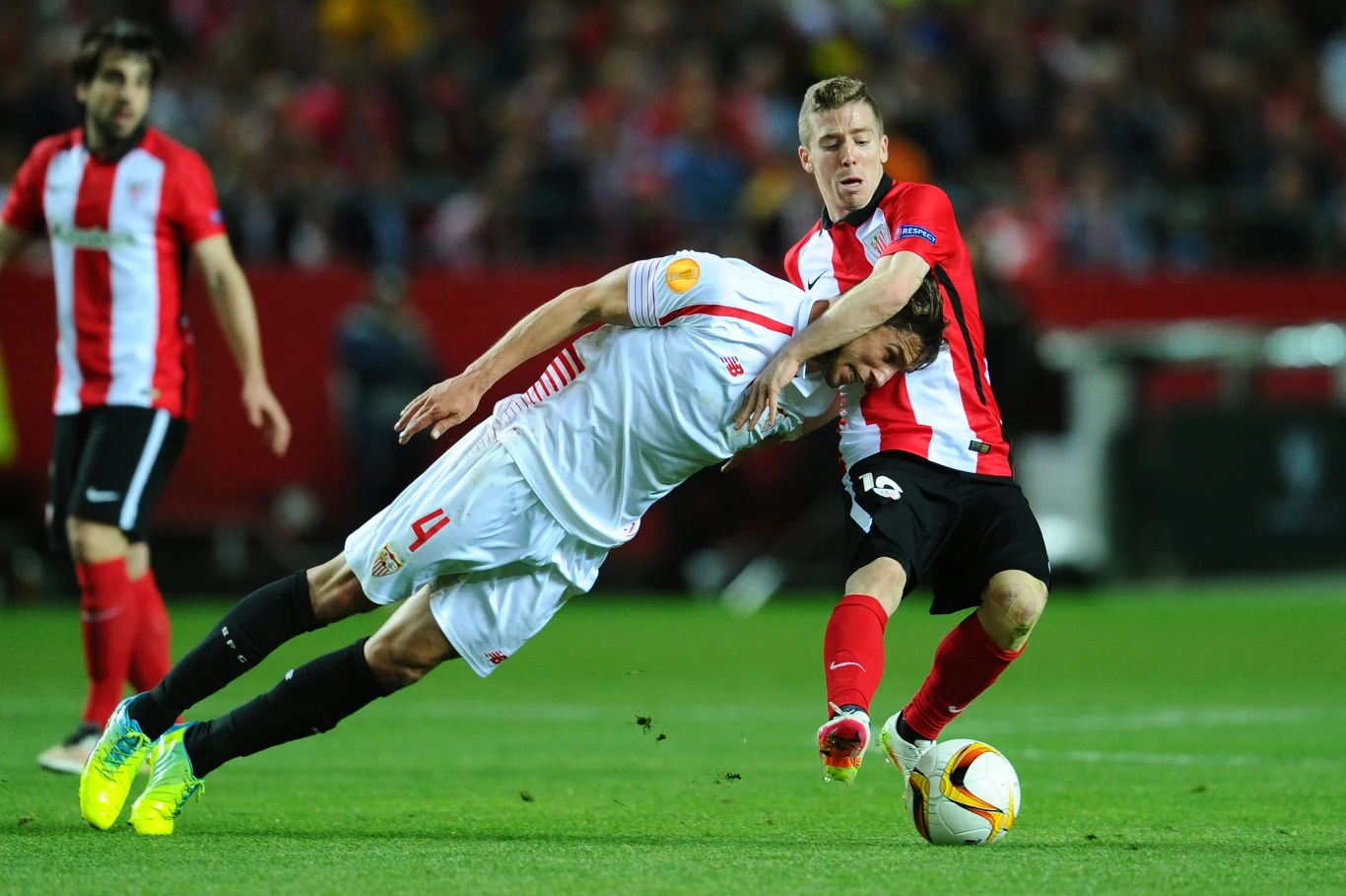 Krychowiak znany był ze swojej nieustępliwości na boisku Dwóch piłkarzy walczy o piłkę podczas intensywnej akcji na boisku, jeden z zawodników w biało-czerwonym stroju jest pochylony do przodu, zatrzymywany przez przeciwnika w czerwono-białej koszulce, a wokół nich rozmyty tłum kibiców.