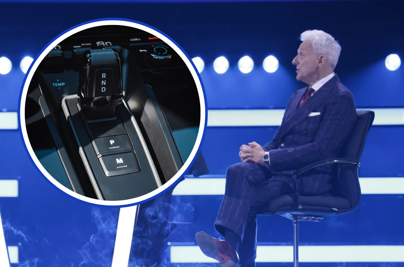 Damian Wyrozumski z Katowic odpadł z programu Milionerzy już na pierwszym pytaniu o automatyczną skrzynię biegów. Starszy mężczyzna w garniturze siedzący na scenie w świetle reflektorów, w lewym rogu widoczny wstawiony detal konsoli zmiany biegów samochodu z oznaczeniami P, R, N, D oraz przyciskiem do zmiany trybu prowadzenia.