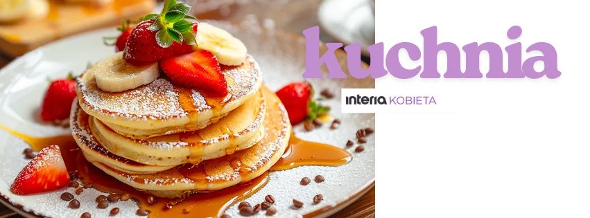 Stos płaskich naleśników udekorowany plasterkami banana, świeżymi truskawkami i posypany cukrem pudrem, polany syropem, otoczony dodatkowymi kawałkami owoców.