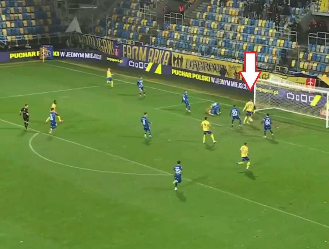 Gol Arki Gdynia w meczu z Górnikiem Zabrze Mecz piłkarski na stadionie, piłkarze w żółto-niebieskich oraz niebieskich strojach walczą o piłkę blisko bramki, większość zawodników zgromadzona w polu karnym, wyraźnie zaznaczony moment pod bramką przy obecności bramkarza i obrońców.