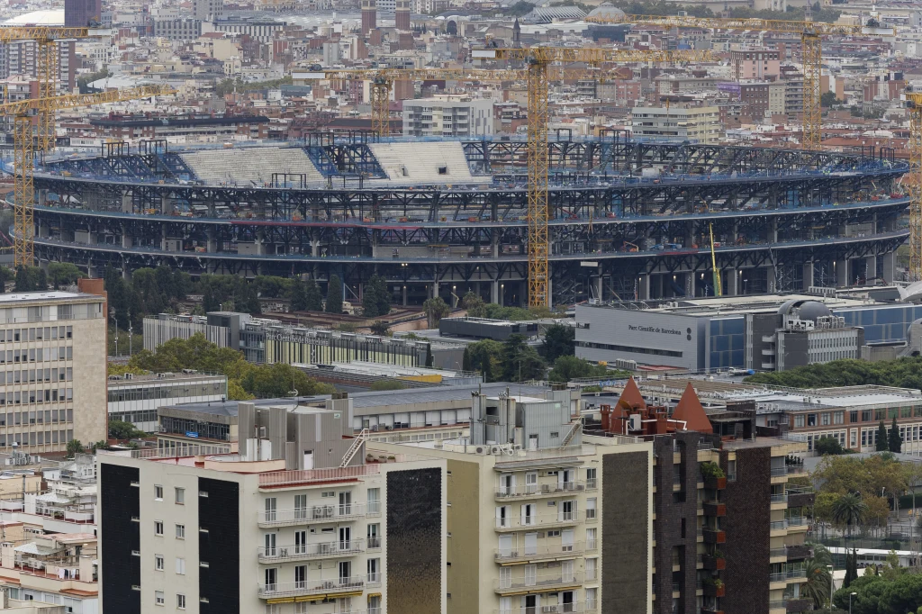 Spotify Camp Nou w trakcie modernizacji Stadion piłkarski w trakcie przebudowy otoczony miejską zabudową i dźwigami budowlanymi, w tle gęsto zabudowane miasto.