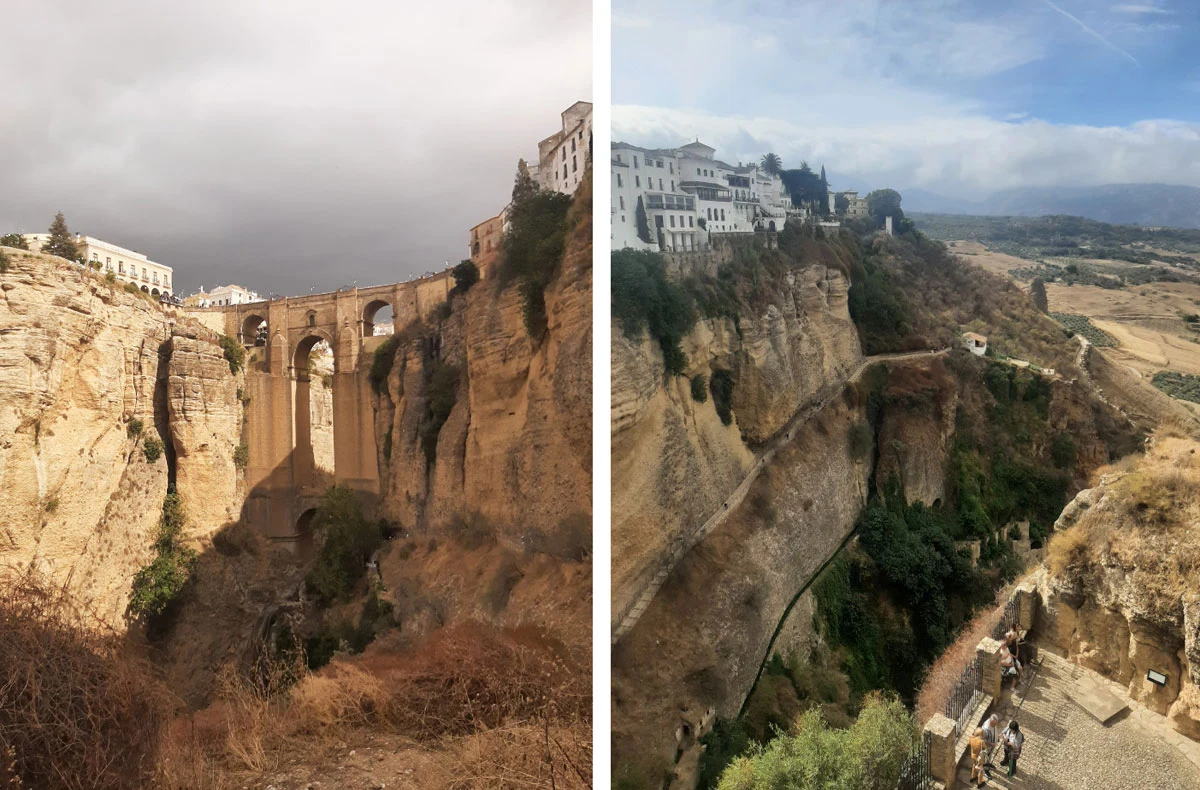 Ronda. Nowy Most i wąwóz El Tojo Kamienny most przebiegający ponad głębokim wąwozem z pionowymi ścianami skalnymi, po jednej stronie mostu białe budynki w stylu andaluzyjskim. Po drugiej stronie przepaści rozciąga się suchy, pagórkowaty krajobraz z rozproszoną roślinnością.