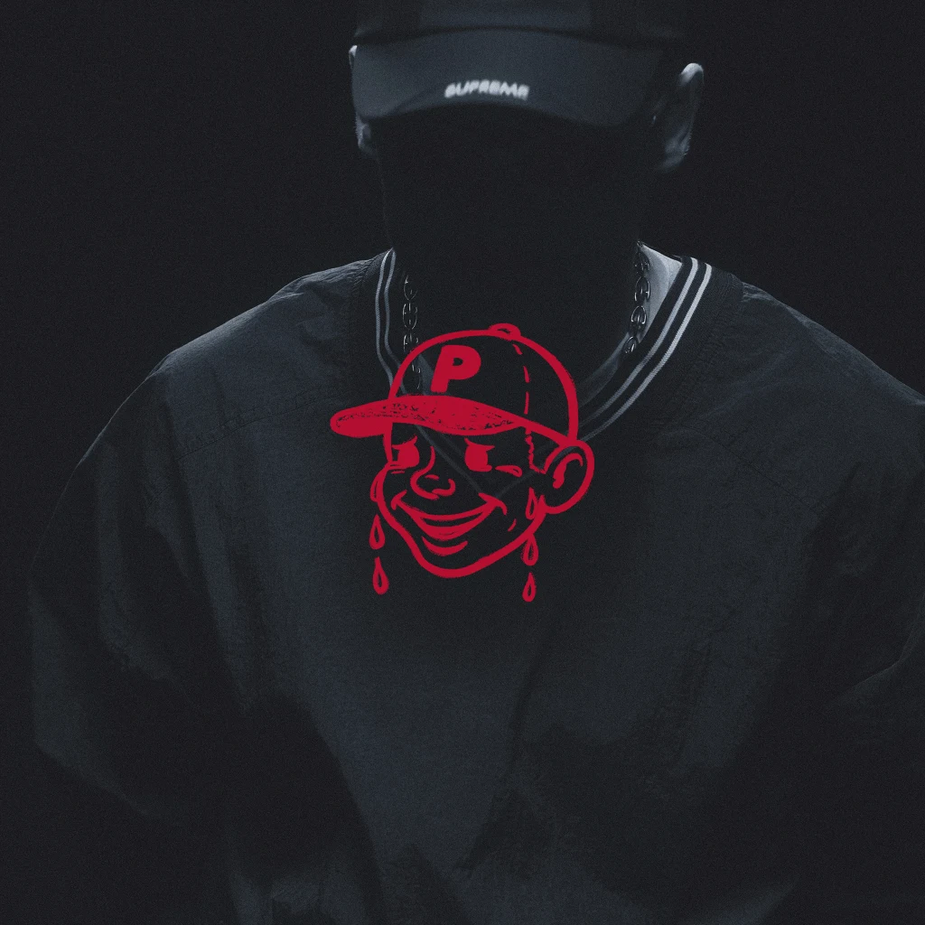 OKładka nowego albumu "Muzyka popularna" Sylwetka osoby w ciemnym ubraniu i czapce z daszkiem, której twarz pozostaje w cieniu, na środku widoczna grafika czerwonej kreskówkowej postaci z literą P na czapce i łzami.