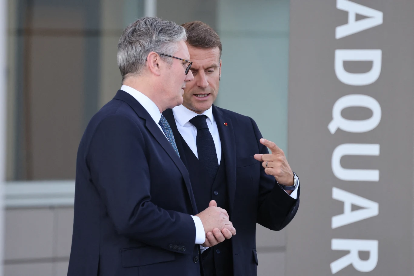 Media donoszą o tajnym spotkaniu "koalicji chętnych" Dwóch elegancko ubranych mężczyzn w garniturach rozmawia ze sobą na tle nowoczesnego budynku z widocznym napisem na elewacji.