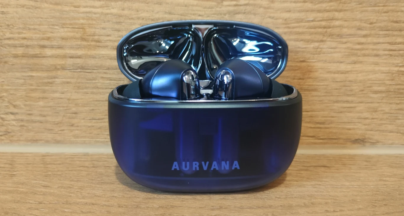 Bezprzewodowe słuchawki douszne umieszczone w otwartym etui ładującym, z wyraźnie widoczną nazwą marki Aurvana na przodzie. Całość na tle drewnianej powierzchni.